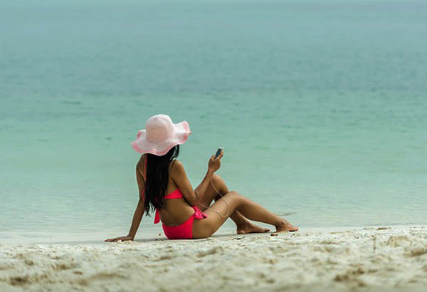 Kvinna på stranden med mobiltelefon